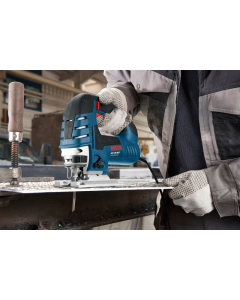 Bosch GST150 BCE Jigsaw shown cutting a metal using a table clamp. Operator in safety clothing. Jigsaw is a corded unit and has adjustment levers.
