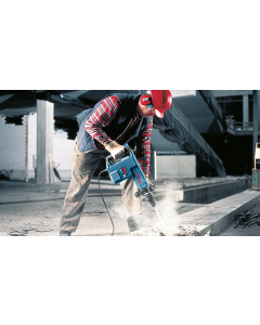 Workman in red check shirt and red safety helmet using a Bosch GSH 11 E medium-duty electric breaker on a construction site. 