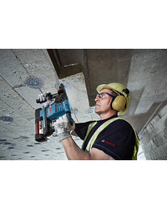 Man wearing a high-visibility vest, ear protectors and safety helmet using a Bosch GBH 36 V-Li Plus Rotary Hammer with SDS Plus. 