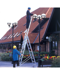 Two men in safety helmets stood on an aluminium three-way ladder while carrying out some work on outdoor lighting.