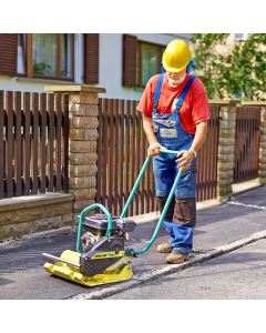 Man wearing a yellow hard hat, blue ear protectors and blue overalls using an Ammann APF 1240 Compactor Plate on pavement.